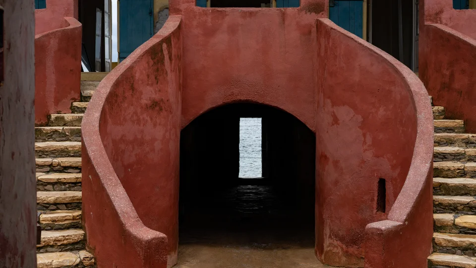 Ruelle colorée sur l’île de Gorée avec maisons historiques et mer en arrière-plan